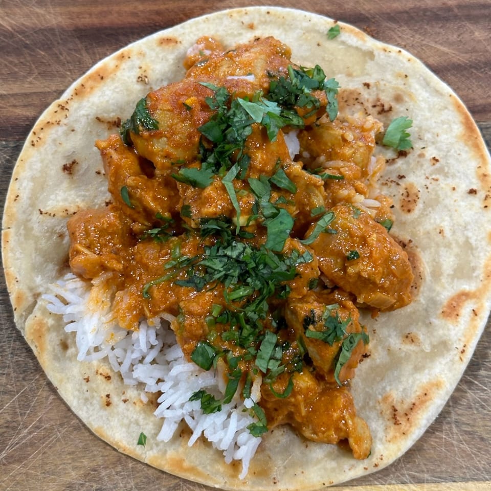 Krazy Taco 937's chicken tikka masala taco with rice and cilantro on a wooden board.