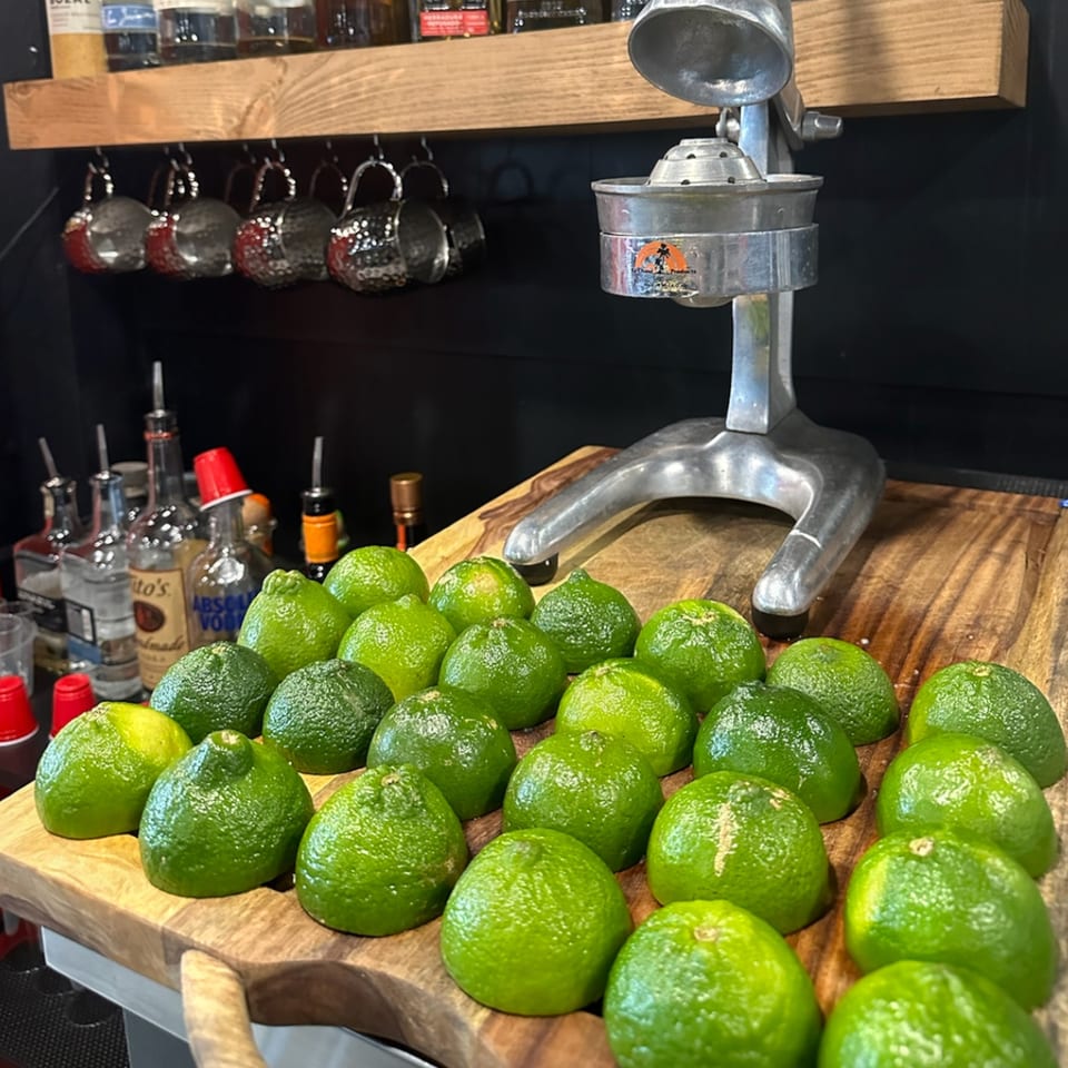 Krazy Taco 937 bar with a manual citrus juicer and many fresh limes on a wooden board.
