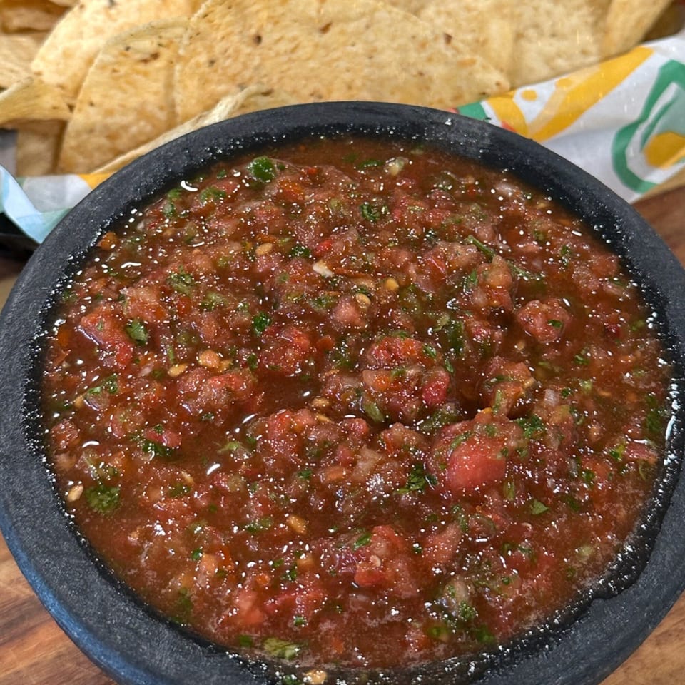 Krazy Taco 937's fresh salsa in a dark bowl, with tortilla chips in the background.