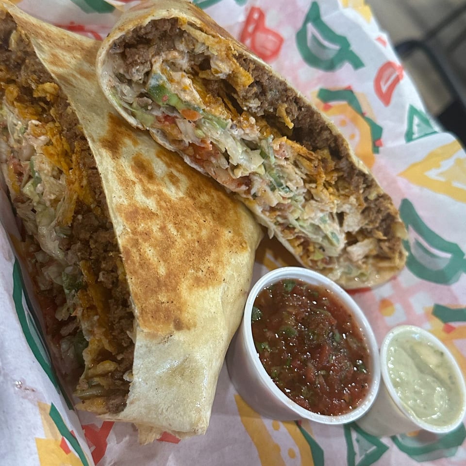 Two Krazy Taco 937 burritos, cut in half, revealing fillings, with salsa and guacamole dips.