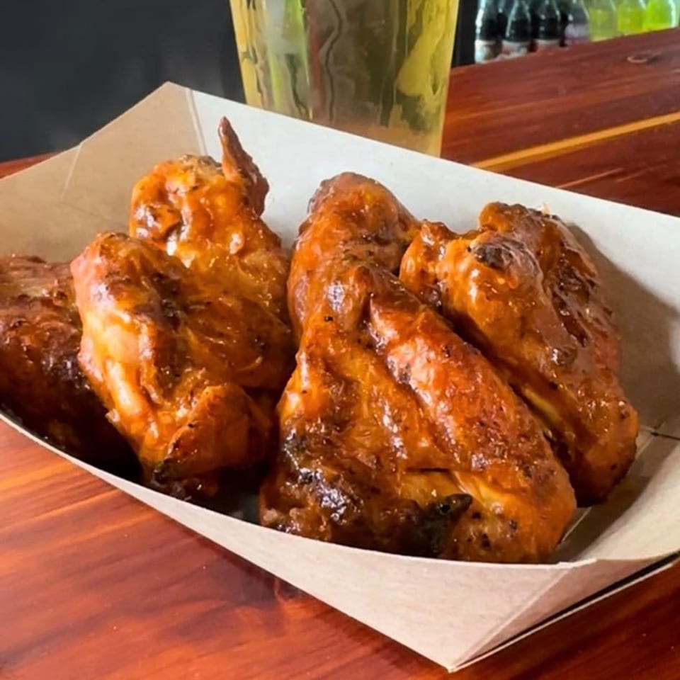 Krazy Taco 937's glazed chicken wings in a paper tray on a wooden table.