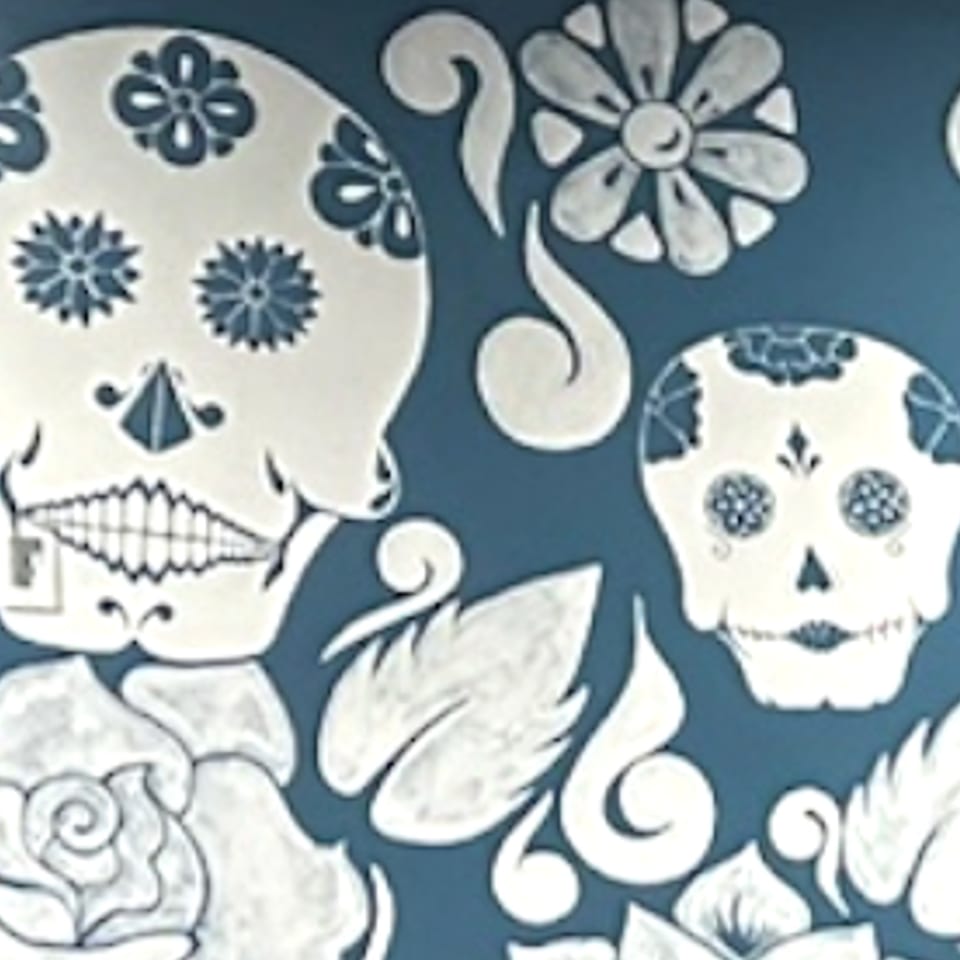 Krazy Taco 937's blue wall with white Day of the Dead sugar skulls and floral designs.