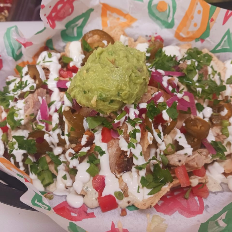 Krazy Taco 937 nachos with guacamole, sour cream, jalapenos, and cilantro in a branded paper tray.