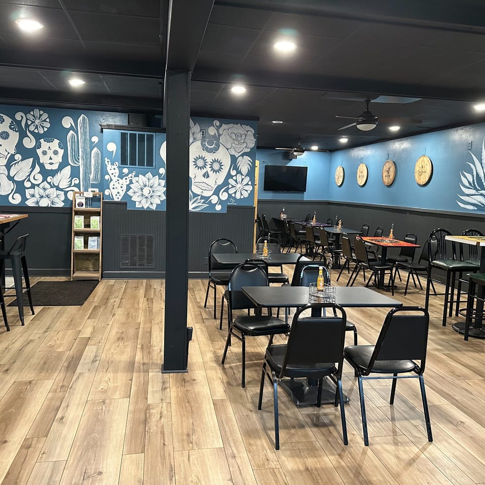 Krazy Taco 937 dining room with blue walls, skull murals, black tables, and wooden floors.